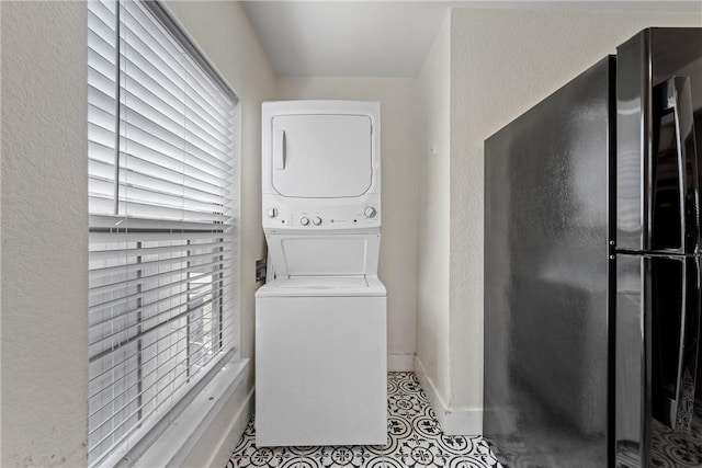 clothes washing area with stacked washing maching and dryer, laundry area, and baseboards