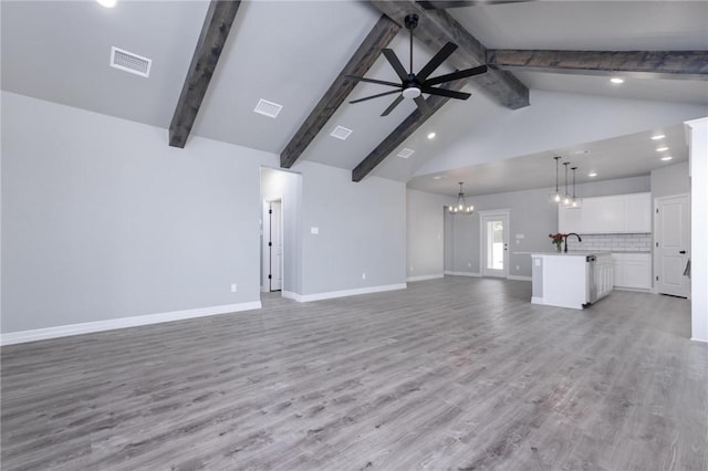 unfurnished living room featuring beam ceiling, ceiling fan with notable chandelier, and light hardwood / wood-style floors