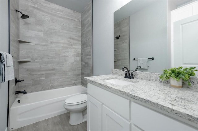 full bathroom featuring hardwood / wood-style flooring, tiled shower / bath combo, toilet, and vanity