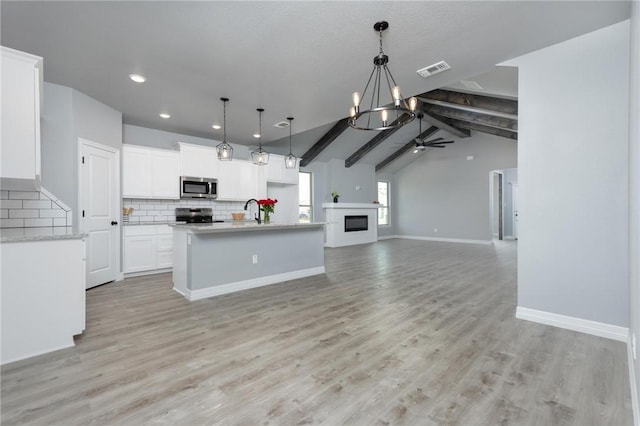 kitchen featuring pendant lighting, white cabinets, ceiling fan with notable chandelier, appliances with stainless steel finishes, and light hardwood / wood-style floors