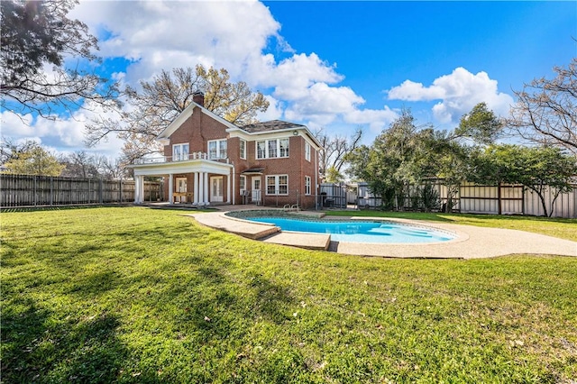 rear view of property featuring a yard and a fenced in pool