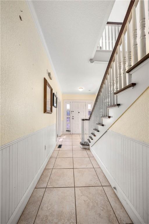 corridor with light tile patterned flooring and ornamental molding