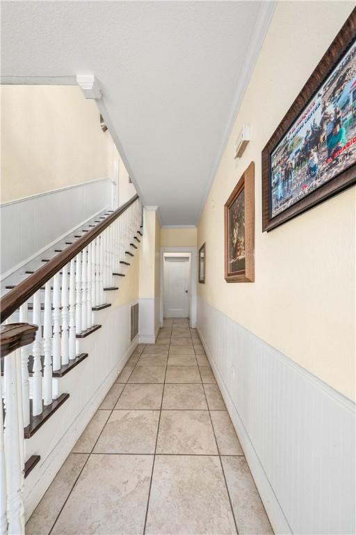 corridor featuring light tile patterned floors and ornamental molding