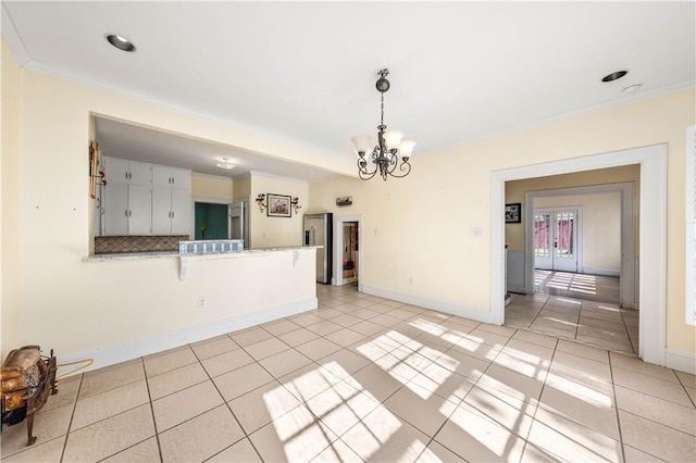 spare room featuring an inviting chandelier, ornamental molding, and light tile patterned flooring