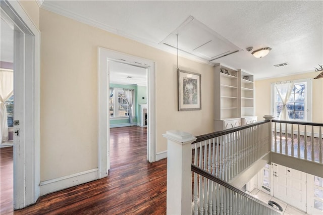 corridor with ornamental molding, a textured ceiling, and dark hardwood / wood-style flooring