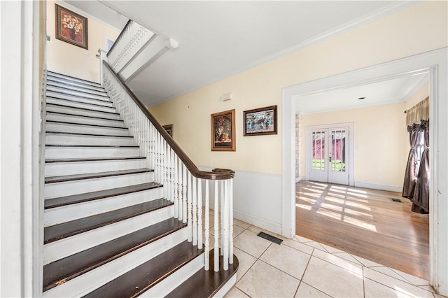 stairs with french doors, tile patterned floors, and crown molding