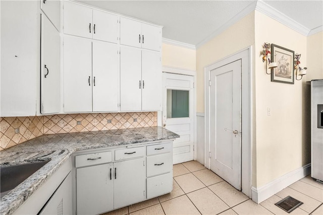 kitchen with ornamental molding, light tile patterned floors, white cabinets, and backsplash