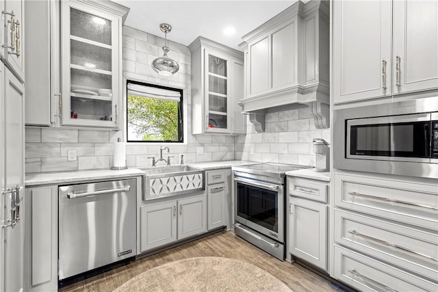 kitchen featuring pendant lighting, sink, decorative backsplash, appliances with stainless steel finishes, and wood-type flooring