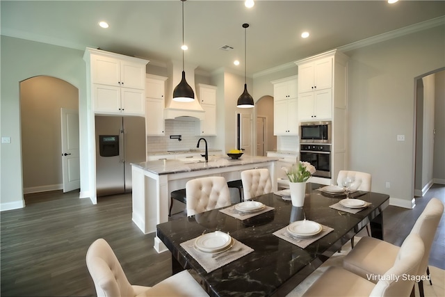 kitchen with light stone countertops, a kitchen island with sink, white cabinets, and stainless steel appliances