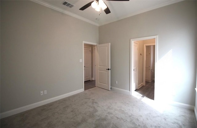 unfurnished bedroom featuring dark colored carpet, ceiling fan, and crown molding