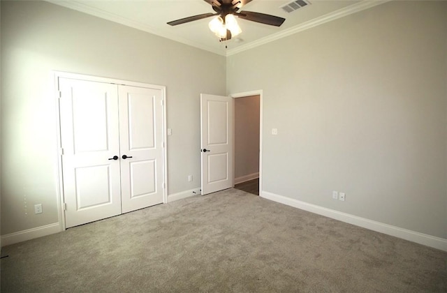 unfurnished bedroom featuring a closet, ceiling fan, crown molding, and carpet