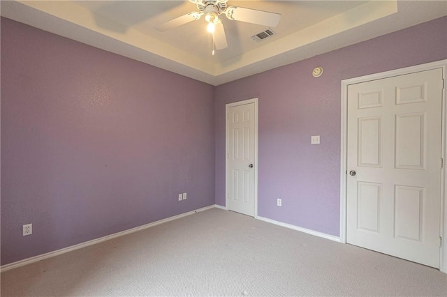 unfurnished room with a tray ceiling, ceiling fan, and carpet flooring