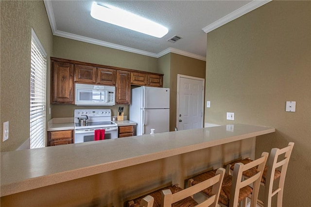 kitchen with white appliances, ornamental molding, a kitchen breakfast bar, and kitchen peninsula