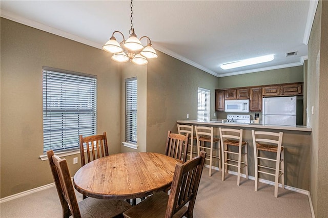 carpeted dining space with an inviting chandelier and ornamental molding