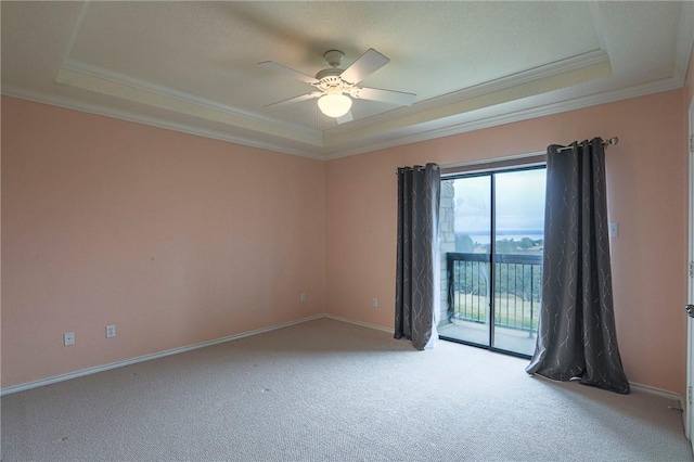 spare room with ceiling fan, ornamental molding, a raised ceiling, and light carpet