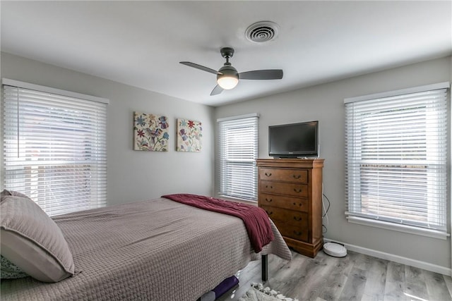 bedroom with multiple windows, ceiling fan, and light hardwood / wood-style flooring