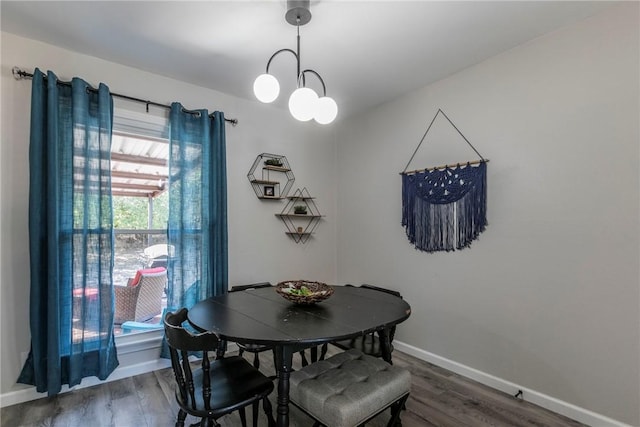 dining room with dark wood-type flooring and an inviting chandelier