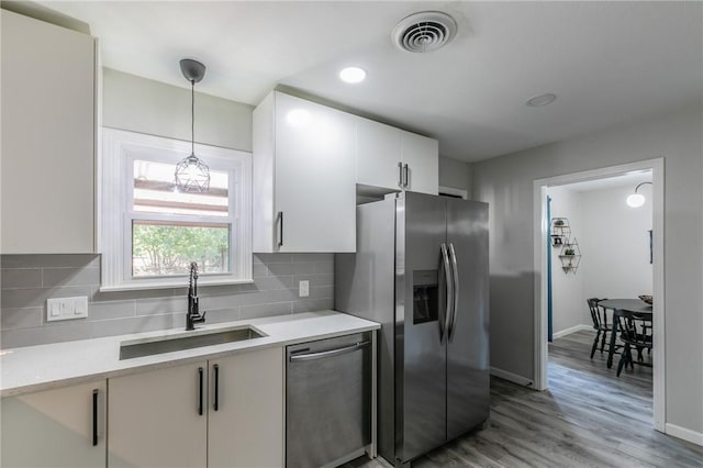 kitchen with white cabinets, sink, tasteful backsplash, light hardwood / wood-style floors, and stainless steel appliances