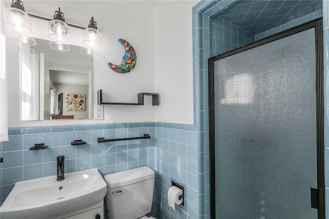 bathroom with vanity, toilet, a shower with door, and tile walls