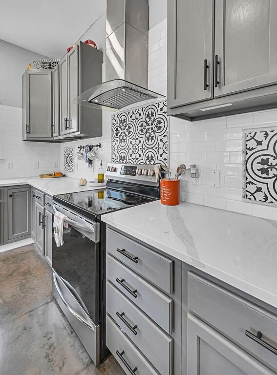 kitchen featuring stainless steel range with electric stovetop, wall chimney exhaust hood, gray cabinetry, and light stone counters