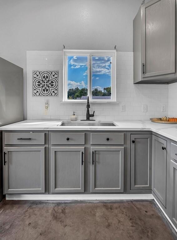 kitchen featuring backsplash, gray cabinetry, and sink