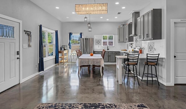 kitchen with a kitchen bar, tasteful backsplash, wall chimney exhaust hood, decorative light fixtures, and gray cabinets