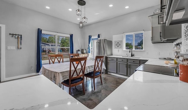 kitchen with stainless steel refrigerator, gray cabinetry, sink, decorative light fixtures, and decorative backsplash