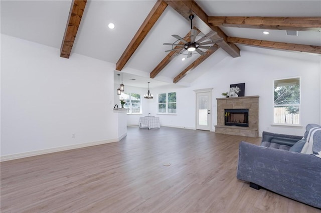 unfurnished living room featuring ceiling fan with notable chandelier, beam ceiling, light wood-type flooring, and a wealth of natural light