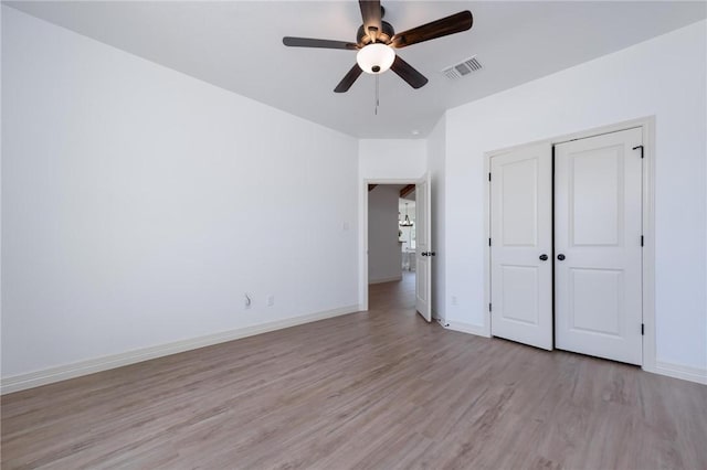 unfurnished bedroom with ceiling fan, light wood-type flooring, and a closet