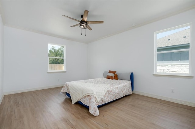 bedroom featuring hardwood / wood-style flooring, ceiling fan, crown molding, and multiple windows