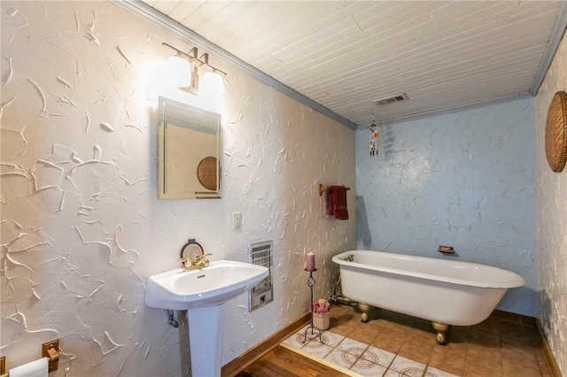 bathroom with baseboards, a freestanding bath, ornamental molding, and a textured wall