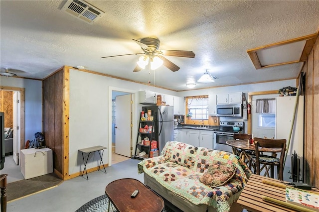 living area featuring visible vents, attic access, concrete flooring, a textured ceiling, and a ceiling fan