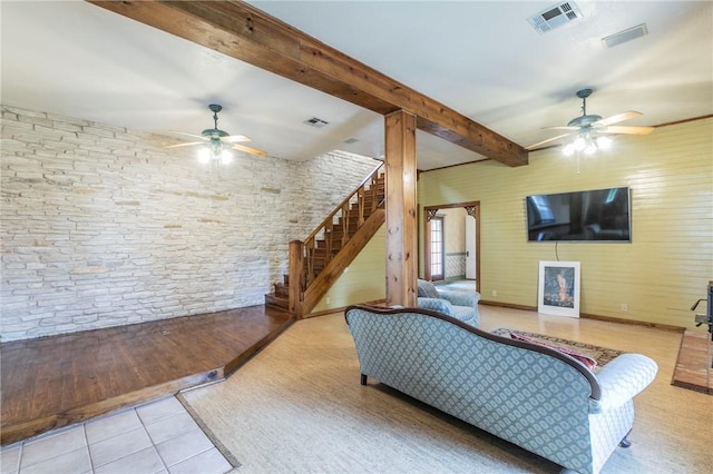 tiled living area featuring visible vents, a ceiling fan, beamed ceiling, and stairs