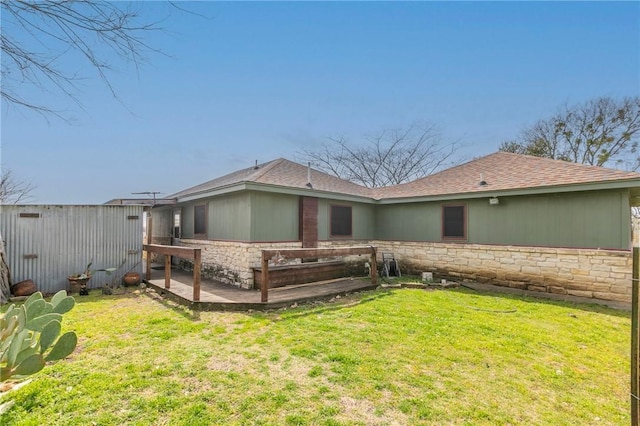 rear view of house with stone siding, a lawn, a patio, and fence