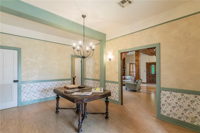 corridor featuring visible vents, wallpapered walls, a wainscoted wall, an inviting chandelier, and wood finished floors