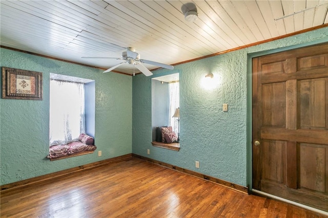 empty room featuring a wealth of natural light, wood finished floors, and a textured wall