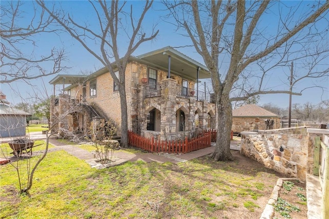 exterior space with stone siding, a balcony, a porch, and a front yard