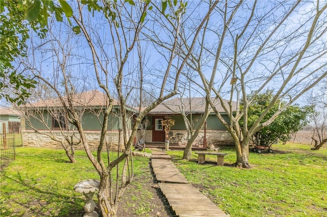 ranch-style home featuring stone siding and a front yard