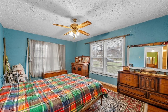 bedroom featuring hardwood / wood-style floors, a textured ceiling, and ceiling fan