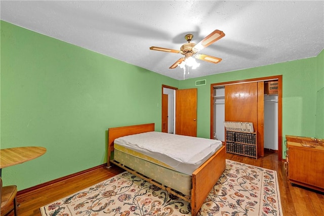 bedroom with a closet, ceiling fan, hardwood / wood-style floors, and a textured ceiling