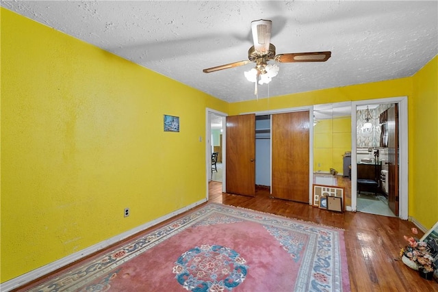 bedroom featuring ceiling fan, hardwood / wood-style floors, and a textured ceiling