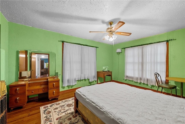 bedroom featuring ceiling fan, wood-type flooring, and a textured ceiling