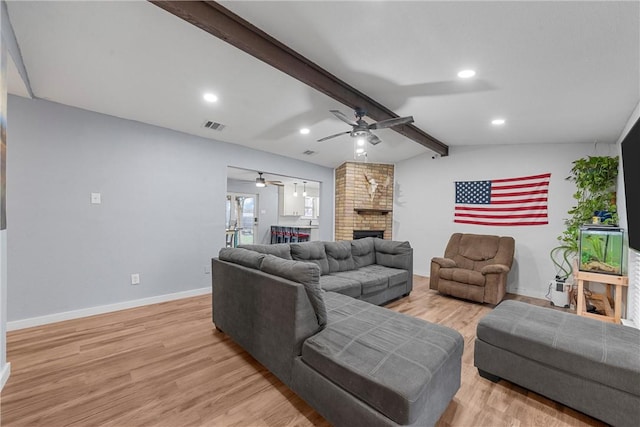 living room featuring light hardwood / wood-style floors, a brick fireplace, ceiling fan, and lofted ceiling with beams