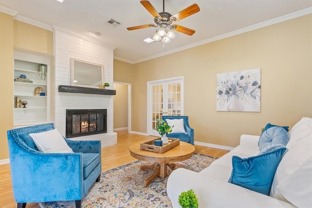 living area featuring visible vents, crown molding, a fireplace, wood finished floors, and a ceiling fan