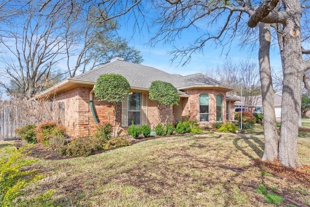 view of front facade featuring a front yard, stone siding, and a shingled roof