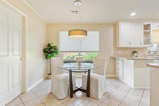 dining room featuring light tile patterned flooring, baseboards, visible vents, and ornamental molding