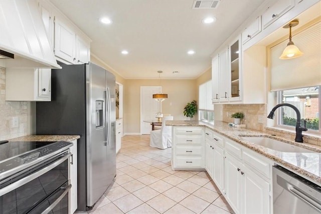 kitchen with premium range hood, visible vents, a sink, white cabinetry, and appliances with stainless steel finishes