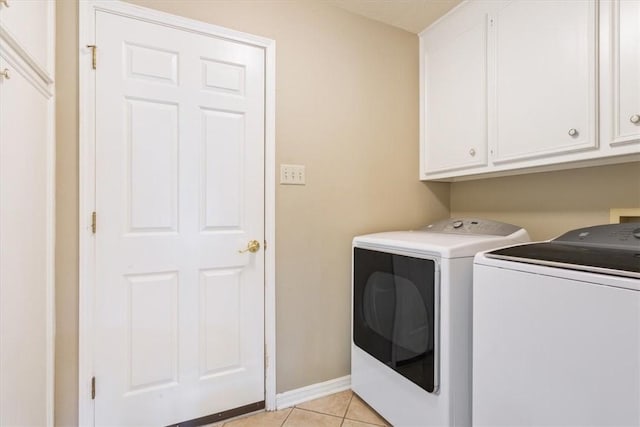 clothes washing area with light tile patterned floors, cabinet space, baseboards, and washing machine and clothes dryer