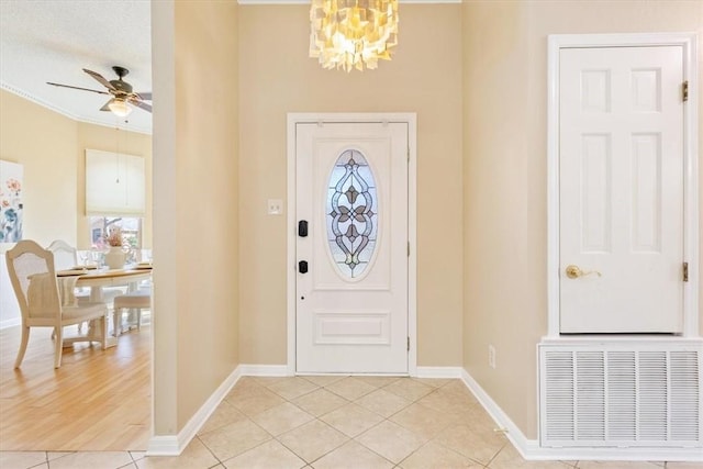 foyer entrance with light tile patterned floors, ceiling fan with notable chandelier, visible vents, and baseboards