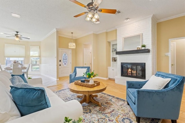 living area with a textured ceiling, crown molding, ceiling fan, and wood finished floors